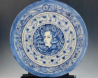 Blue and white 11” wide one of a kind plate for wall with lady portrait. Unique plate can be used for serving also. Plate Hanger is secure