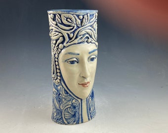 Blue and white one of a kind ceramic sculpted face vase in blue and white. 9 inches tall with hand sculpted face and elaborate hand carving