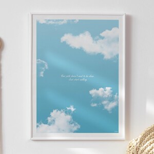 May include: A framed print featuring a blue sky with fluffy white clouds. The artwork includes the text "Your path doesn't need to be clear. Just start walking." A decorative macrame wall hanging and a woven basket are visible.