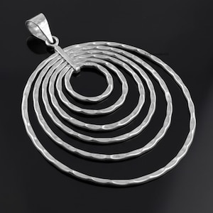Peut inclure: Pendentif argenté composé d'une série de cercles concentriques martelés. Le pendentif a une surface texturée et une boucle pour une chaîne. Le design est moderne et géométrique, adapté au quotidien ou aux occasions spéciales.