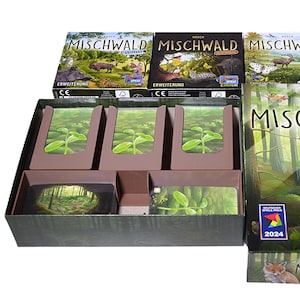 Könnte beinhalten: Ein Brettspiel namens "Mischwald" mit Waldmotiven. Die Schachtel zeigt einen Fuchs, ein Reh und eine Waldszene. Die offene Schachtel zeigt Spielkomponenten, darunter Karten und Trennwände. Die Spielbox ist etwa 30 cm lang.