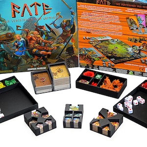 Könnte beinhalten: Ein Brettspiel mit dem Titel "FATE Die Verteidiger von Grimheim" mit farbenfrohen Illustrationen von Kriegern. Enthält Spielsteine, Karten, Würfel und schwarze Tabletts. Die Spielkomponenten sind auf einer weißen Oberfläche angeordnet.