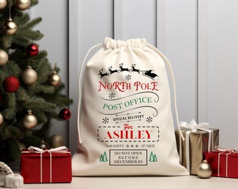 Può includere: Un sacco regalo color crema con coulisse con le parole "North Pole Post Office" e "Special Delivery" stampate in nero e rosso. La borsa è personalizzata "Per Ashley" e include una lista di controllo "Naughty or Nice" e il testo "Do Not Open Before December 25".