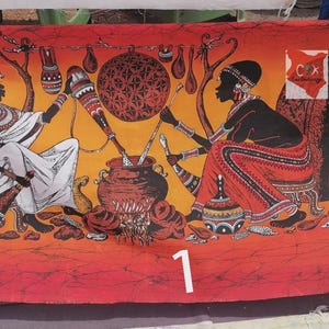 Pode incluir: Um tecido retangular com uma ilustração de tema africano. São retratadas duas figuras, uma em branco e outra em vermelho, envolvidas num ritual. O fundo é laranja e amarelo, com um grande desenho central e vários elementos decorativos. O número "1" está na parte inferior.