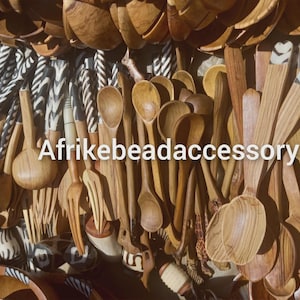 Può includere: Una collezione di cucchiai, forchette e ciotole di legno. Alcuni manici sono dipinti con motivi bianchi e neri. Il testo "Afrikebeadaccessory" è visibile in bianco. Gli articoli sono di varie tonalità di marrone.