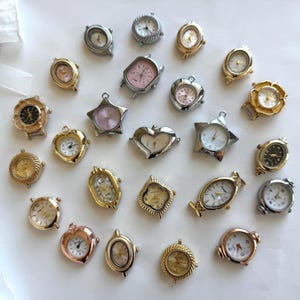 Könnte beinhalten: Eine Sammlung von zweiundzwanzig kleinen Uhrenzifferblättern in verschiedenen Formen wie Herzen, Sternen, Ovalen und Kreisen. Die Zifferblätter haben goldene, silberne und roségoldene Metalloberflächen mit weißen, schwarzen und rosafarbenen Zifferblättern.