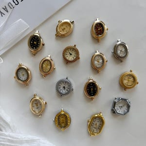 May include: A collection of fifteen small watch faces in various shapes and metallic finishes, including gold and silver tones. Each piece features a dial with hour markers and hands, designed as individual components for jewelry making or repair.