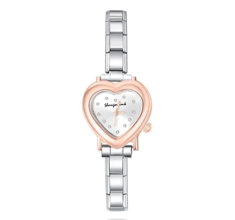 May include: A silver and rose gold wristwatch with a heart-shaped face. The watch has a silver band and a white watch face with small, round markers. The watch face has the text "Shanzin ink" in cursive.