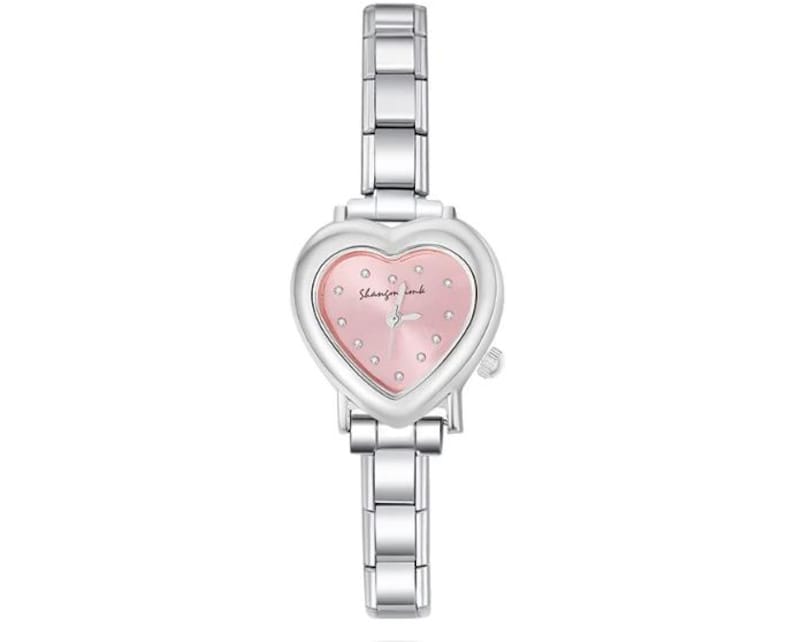 May include: A silver-toned wristwatch with a heart-shaped face and a pink dial. The watch features a linked metal band and small, sparkling accents on the face. The text "Shanzin imb" is visible on the watch face.