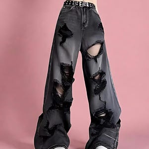 Pu&ograve; includere: Jeans neri strappati con ampi strappi e lacerazioni. I pantaloni a gamba larga presentano una cintura nera borchiata e scarpe da ginnastica bianche. I jeans hanno un aspetto sbiadito, perfetto per uno stile casual e audace.
