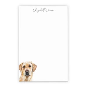 May include: A notepad with the name "Elizabeth Davis" printed at the top. A golden retriever dog's head is peeking out from the bottom left corner of the notepad.