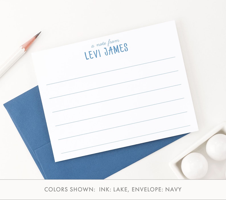 May include: A white card with blue lines and the text "a note from LEVI JAMES" printed in blue. The card is on top of a blue envelope. The text "COLORS SHOWN: INK: LAKE, ENVELOPE: NAVY" is printed below the card.