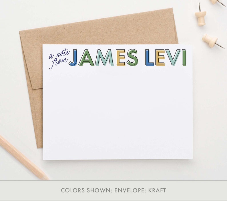 K&ouml;nnte beinhalten: Eine wei&szlig;e Briefpapierkarte mit einem Kraftumschlag. Die Karte tr&auml;gt den Text "a note from" in Kursivschrift und den Namen "JAMES LEVI" in bunten Blockbuchstaben mit schwarzen Umrandungen.