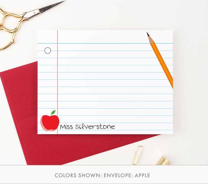 May include: A white lined notepad with a red apple and the text "Miss Silverstone". The notepad is on a red envelope.