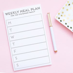 May include: A white weekly meal planner with the text "WEEKLY MEAL PLAN FOR THE STEVENSON FAMILY" at the top. The planner has spaces for each day of the week, Monday through Sunday, with the first letter of each day of the week listed on the left side.