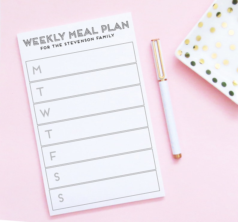 May include: A white weekly meal planner with the text "WEEKLY MEAL PLAN FOR THE STEVENSON FAMILY" at the top. The planner has spaces for each day of the week, Monday through Sunday, with the first letter of each day of the week listed on the left side.
