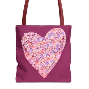 Può includere: Una borsa tote con un grande cuore composto da cuori più piccoli nei toni del rosa, viola e pesca. La borsa ha uno sfondo magenta scuro e cinturini bordeaux abbinati. Questa borsa tote è adatta per trasportare libri, generi alimentari o oggetti personali.