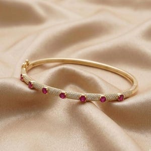 Bracelet jonc imposant en argent plaqué or 14 carats, orné de rubis roses et de diamants.