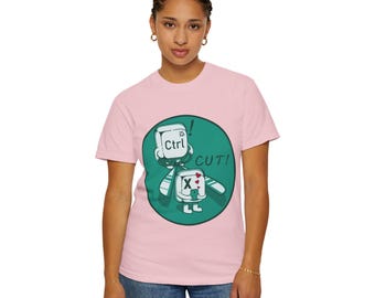 May include: A light pink t-shirt featuring a cartoon character with a Ctrl key head and an X key body, set against a teal green circle. The text "CUT!" is also displayed. The shirt is made of a soft material.