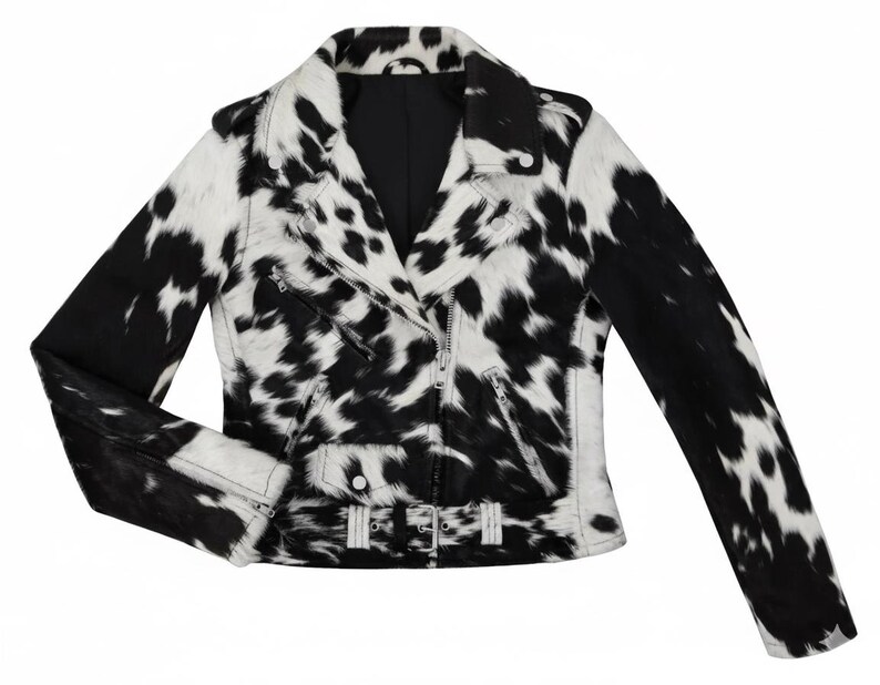 May include: A black and white cow print motorcycle jacket featuring a notched collar, silver-tone metal zippers on the front and cuffs, a small flap pocket, and an adjustable waist belt with a silver buckle, all in a textured finish.