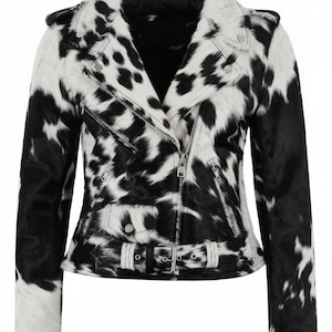 May include: A moto-style jacket featuring a black and white cow-print pattern with a textured finish. The jacket includes a notched lapel, an asymmetrical silver-tone metal zipper closure, zippered pockets, shoulder epaulets, and a buckled waist belt.