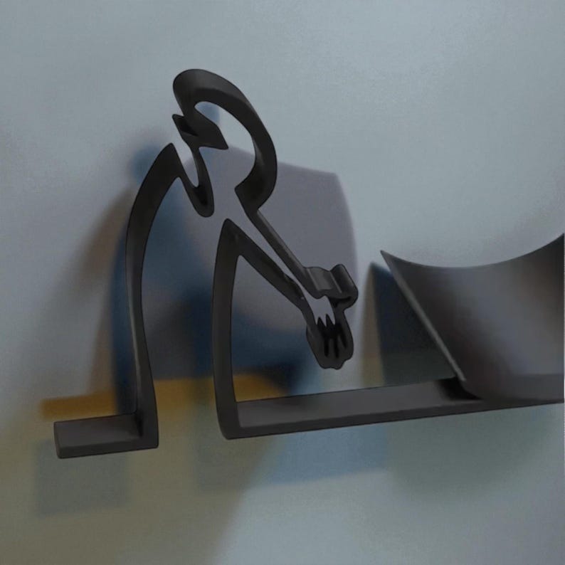 May include: A dark gray, stylized wall-mounted sculpture depicting a person. The figure is in a seated position, with arms extended. The sculpture is mounted on a light gray background, with a shelf-like element extending from the base.