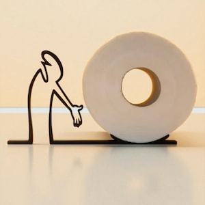 May include: A whimsical toilet paper holder featuring a black metal silhouette of a person reaching towards a roll of white toilet paper. The holder has a minimalist design, suitable for a modern bathroom.