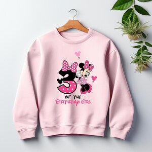 Puede incluir: Sudadera rosa claro con un dise&ntilde;o de Minnie Mouse y el n&uacute;mero 3 con lunares. El texto "OF THE BIRTHDAY GIRL" est&aacute; debajo. La sudadera tiene cuello redondo y mangas largas.
