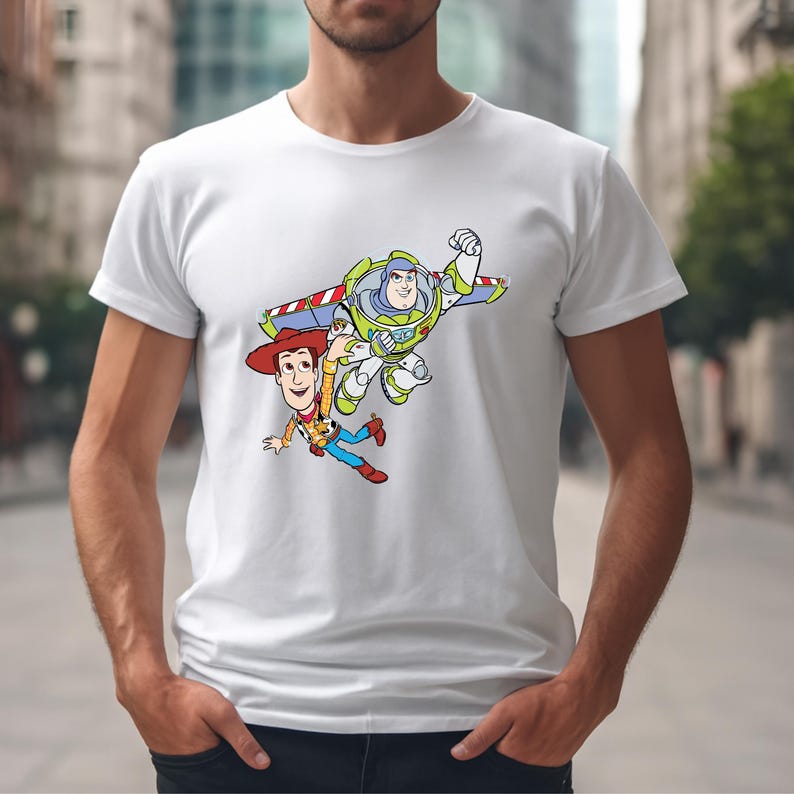 K&ouml;nnte beinhalten: Wei&szlig;es T-Shirt mit einem farbenfrohen Aufdruck von Woody und Buzz Lightyear aus Toy Story. Woody tr&auml;gt einen Cowboyhut und Buzz einen Raumanzug. Das Design befindet sich mittig auf dem Shirt.