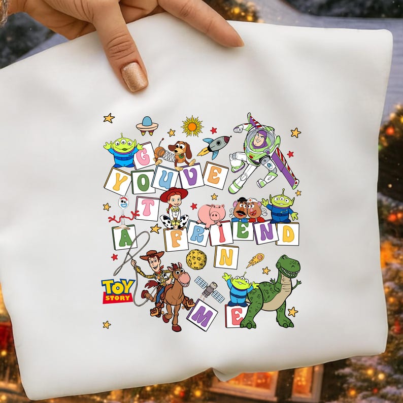 Puede incluir: Sudadera blanca con un gr&aacute;fico colorido de personajes de Toy Story y la frase "You've Got a Friend in Me". El dise&ntilde;o incluye a Woody, Buzz Lightyear y otros personajes de la pel&iacute;cula animada, rodeados de estrellas.