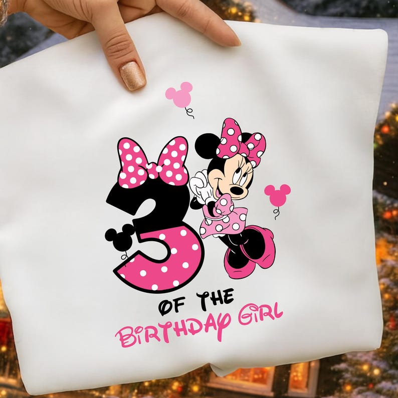 Puede incluir: Camiseta blanca con un gr&aacute;fico de Minnie Mouse, con un lazo y un vestido de lunares rosas. El n&uacute;mero "3" es en negro con un dise&ntilde;o de lunares rosas. El texto dice "OF THE BIRTHDAY GIRL".