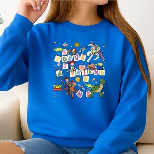 Puede incluir: Una sudadera azul real con un gr&aacute;fico colorido de personajes de la pel&iacute;cula animada "Toy Story". La frase "You've Got A Friend In Me" se muestra en letras de bloque. La sudadera tiene cuello redondo.