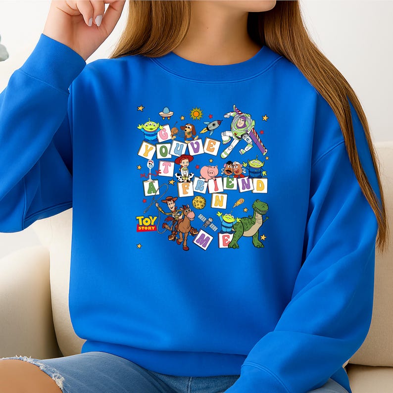 Puede incluir: Una sudadera azul real con un gr&aacute;fico colorido de personajes de la pel&iacute;cula animada "Toy Story". La frase "You've Got A Friend In Me" se muestra en letras de bloque. La sudadera tiene cuello redondo.