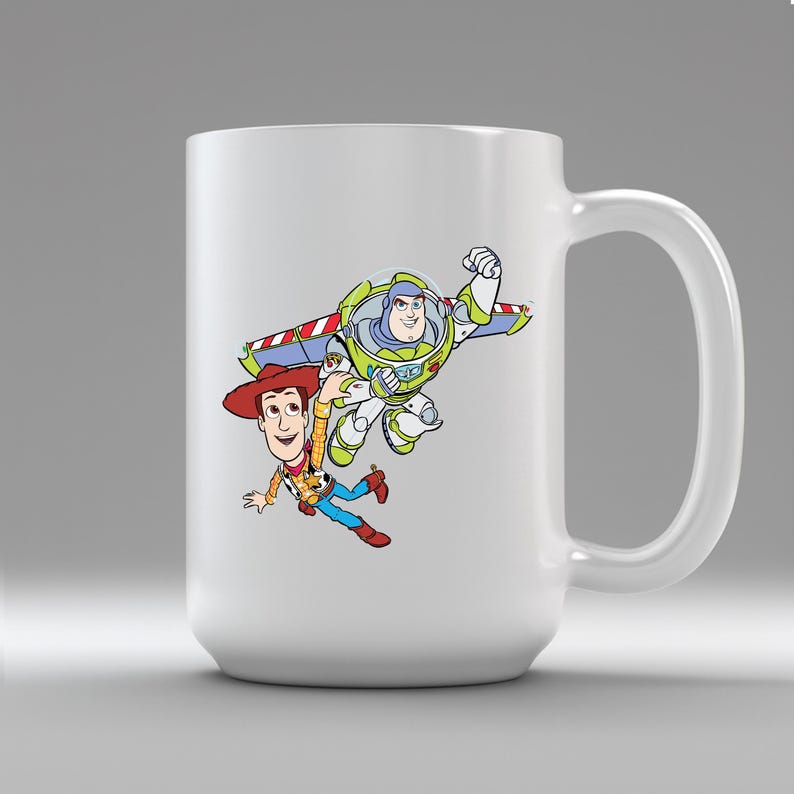 K&ouml;nnte beinhalten: Wei&szlig;er Keramikbecher mit einer farbenfrohen Grafik von Buzz Lightyear und Woody aus Toy Story. Buzz ist in einer Flugpose und Woody f&auml;llt. Der Becher hat einen gro&szlig;en Henkel. Geeignet f&uuml;r Hei&szlig;- und Kaltgetr&auml;nke.