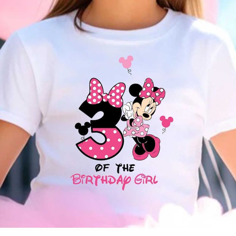 Puede incluir: Camiseta blanca con un dise&ntilde;o de Minnie Mouse. El dise&ntilde;o incluye un gran n&uacute;mero 3 con lunares rosas, Minnie Mouse y el texto "OF THE BIRTHDAY GIRL" en rosa. La camiseta tiene mangas cortas.