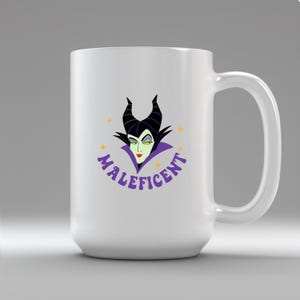 Puede incluir: Taza de cer&aacute;mica blanca con una imagen de dibujos animados de Mal&eacute;fica, con cuernos negros, piel verde y un cuello morado. La palabra "Mal&eacute;fica" est&aacute; en escritura morada. La taza tiene un asa grande.