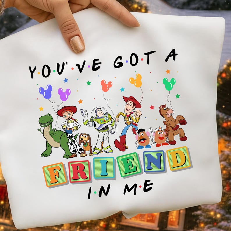 May include: White sweatshirt featuring a colorful graphic of Toy Story characters with the text "YOU'VE GOT A FRIEND IN ME". The design includes Woody, Buzz Lightyear, and other characters from the movie.