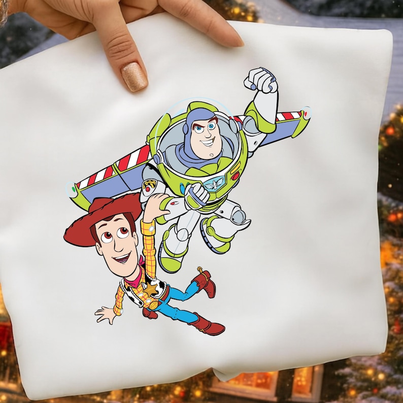 K&ouml;nnte beinhalten: Wei&szlig;er Kissenbezug mit einer farbenfrohen Grafik von Buzz Lightyear und Woody aus Toy Story. Buzz Lightyear tr&auml;gt einen gr&uuml;nen und wei&szlig;en Raumanzug, und Woody tr&auml;gt einen Cowboyhut und eine Weste.