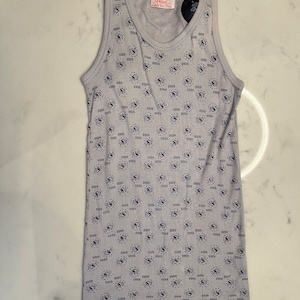 May include: A grey sleeveless undershirt with a repeating pattern of a stylised "USA" logo. The shirt has a small tag that reads "Robert Stanton Made in USA".