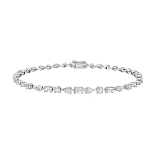 Könnte beinhalten: Ein filigranes Silberarmband mit einer Reihe verschieden geformter Edelsteine, darunter Smaragdschliff, Tropfenform und runde Diamanten. Das Armband wird mit einem Verschluss gesichert, vor weißem Hintergrund.