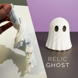 May include: A white 3D printed ghost figurine with oval eyes and a spiral-textured body. The object is shown in two views: one side-profile view displaying the layered structure and one front-facing view with the text RELIC GHOST printed below.
