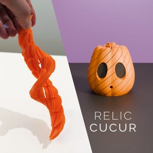 Könnte beinhalten: Ein orangefarbenes, 3D-gedrucktes Spiralobjekt und eine orangefarbene kürbisförmige Figur mit zwei ovalen Augen und einem kleinen runden Mund. Der Text RELIC CUCUR ist in Weiß unter der Figur gedruckt, die diagonale Linien auf der Oberfläche hat.