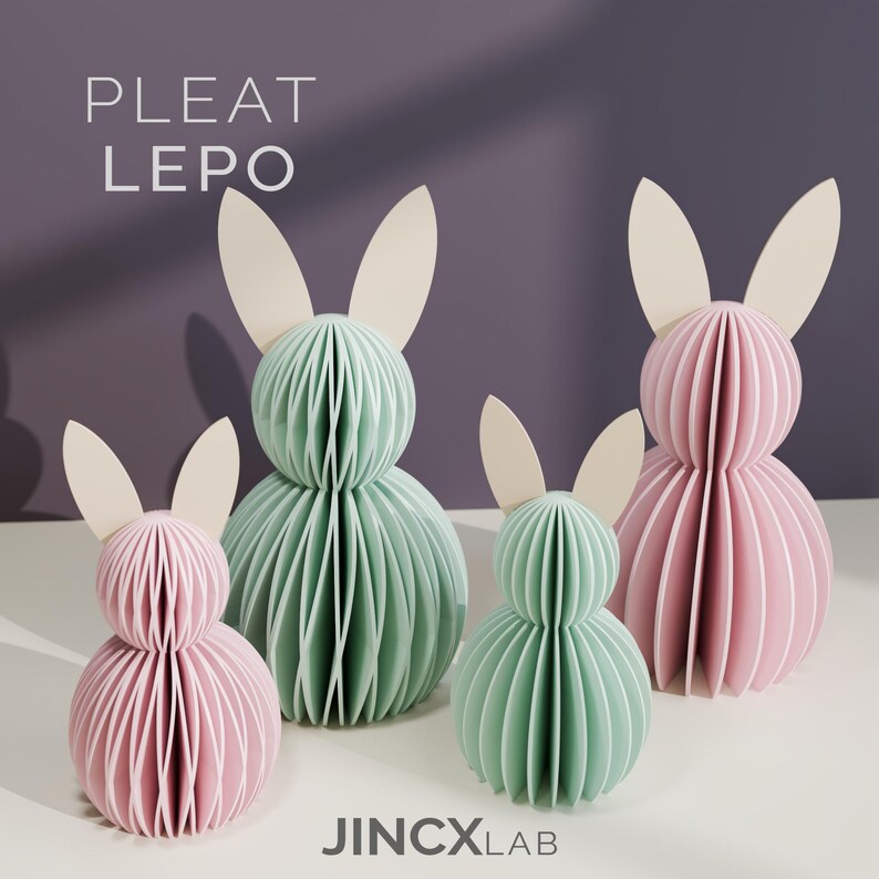 Puede incluir: Cuatro esculturas de conejos de papel en colores pastel. Dos son rosas y dos verde menta, con orejas color crema. Los conejos est&aacute;n hechos de papel plisado, con el texto "PLEAT LEPO" y "JINCXLAB" visibles.