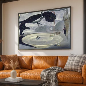 Puede incluir: Pintura surrealista enmarcada que presenta un plato grande con objetos, un objeto negro con una lágrima y una figura. La obra de arte está ambientada sobre un fondo de cielo nublado y montañas. La pintura se exhibe sobre un sofá de cuero marrón.