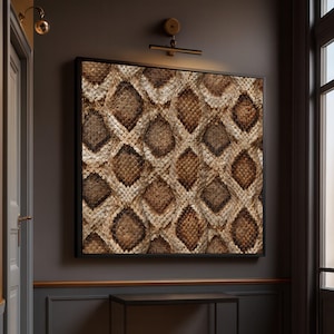 Op de afbeelding: Een rechthoekig wandkunstwerk met een herhalend ruitpatroon dat de textuur en het uiterlijk van slangenleer nabootst. Het ontwerp toont een kleurenpalet van verschillende tinten bruin, beige en crème, omlijst door een dunne zwarte lijst.