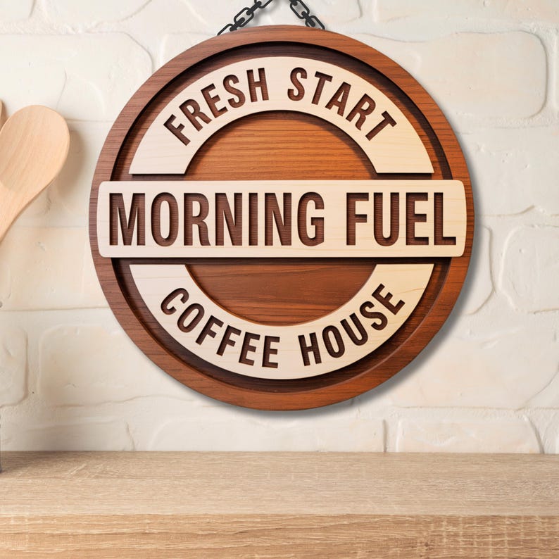 Puede incluir: Un letrero redondo de madera con las palabras "FRESH START", "MORNING FUEL" y "COFFEE HOUSE" en madera clara sobre un fondo de madera oscura. El letrero est&aacute; colgado de una cadena.