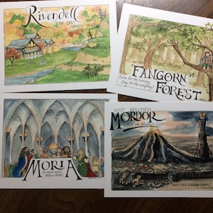 K&ouml;nnte beinhalten: Vier illustrierte Postkarten, die verschiedene Orte aus Der Herr der Ringe zeigen. Die erste Postkarte zeigt eine Aquarellillustration von Rivendell, einem Dorf mit einem Fluss und gr&uuml;nen H&uuml;geln. Die zweite Postkarte zeigt eine Aquarellillustration von Fangornwald, einem dichten Wald mit hohen B&auml;umen. Die dritte Postkarte zeigt eine Aquarellillustration von Moria, einer gro&szlig;en unterirdischen Stadt mit vielen B&ouml;gen und einem Tisch, an dem Menschen sitzen. Die vierte Postkarte zeigt eine Aquarellillustration von Mordor, einem dunklen und trostlosen Land mit einem Vulkan und einem Turm.