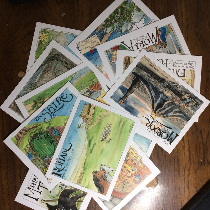 K&ouml;nnte beinhalten: Eine Sammlung von bunten, illustrierten Karten verschiedener Orte aus dem Universum des Herrn der Ringe. Die Karten sind auf wei&szlig;em Karton gedruckt und zeigen handgezeichnete Illustrationen von ikonischen Sehensw&uuml;rdigkeiten und Charakteren. Die Karten beinhalten Orte wie Mordor, Rohan, das Auenland und Moria.