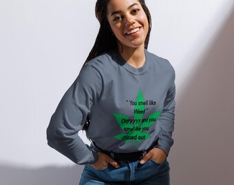 May include: A gray long-sleeve shirt with a green cannabis leaf design and the text "You smell like Weed. Ol'yyyyy and you smell like you missed out." The shirt is paired with blue jeans.
