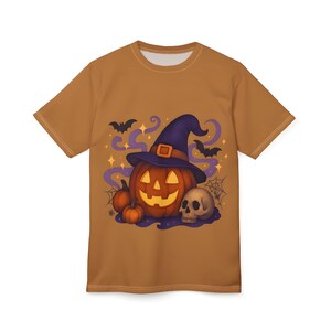 May include: A brown t-shirt featuring a Halloween-themed graphic. The design includes a jack-o'-lantern wearing a witch's hat, bats, a skull, and pumpkins. The artwork is surrounded by purple swirls and stars.